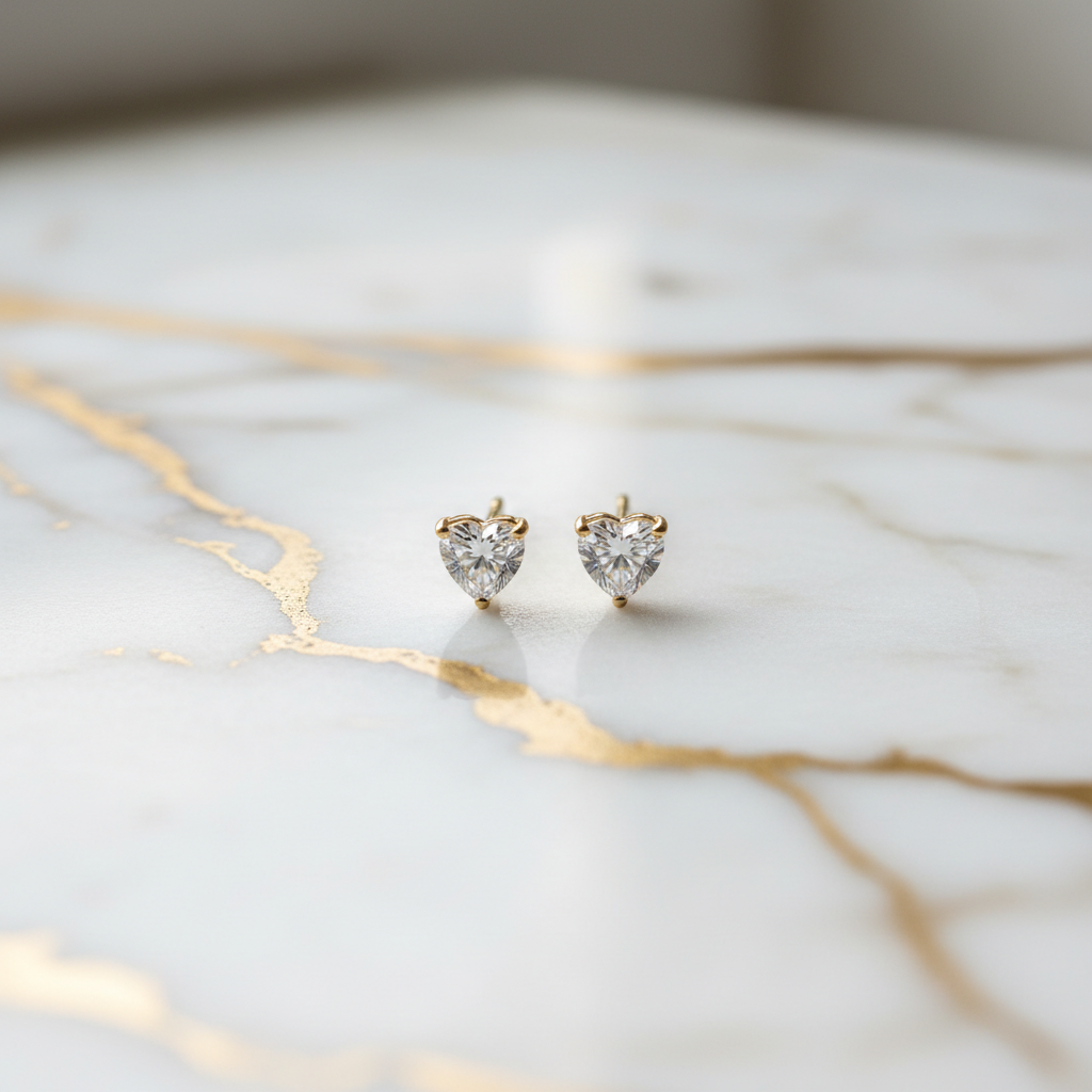 Small heart studs on white marble with gold veining